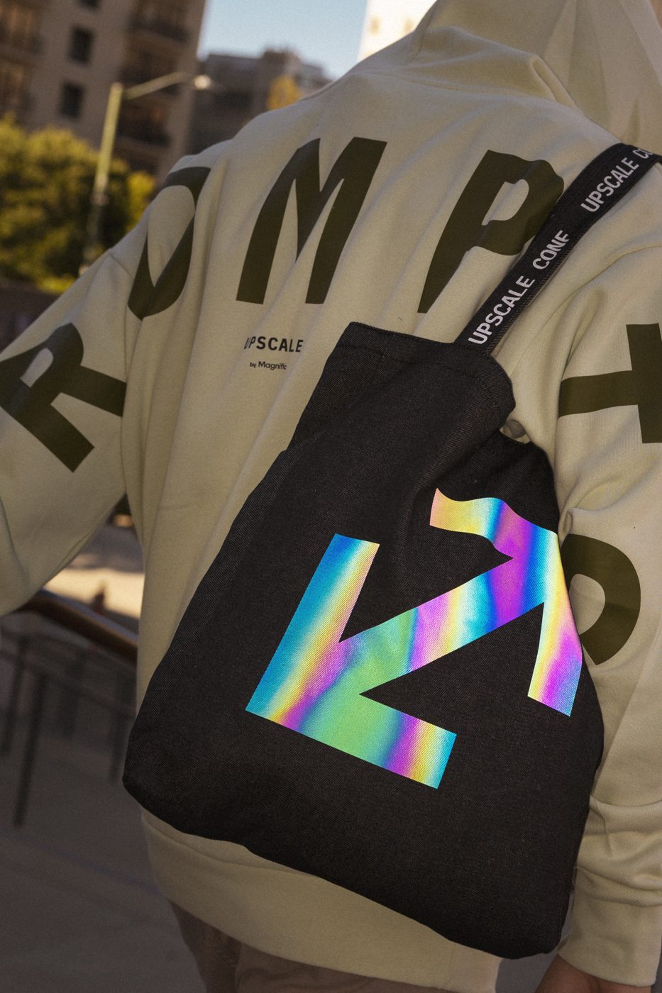 Upscale denim tote with iridescent logo, worn over a PROMPT hoodie